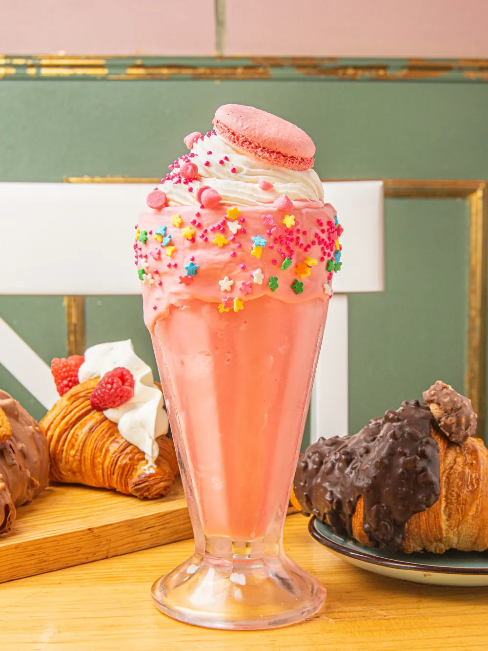Malteada rosa con crema batida, chispas y un macaron encima