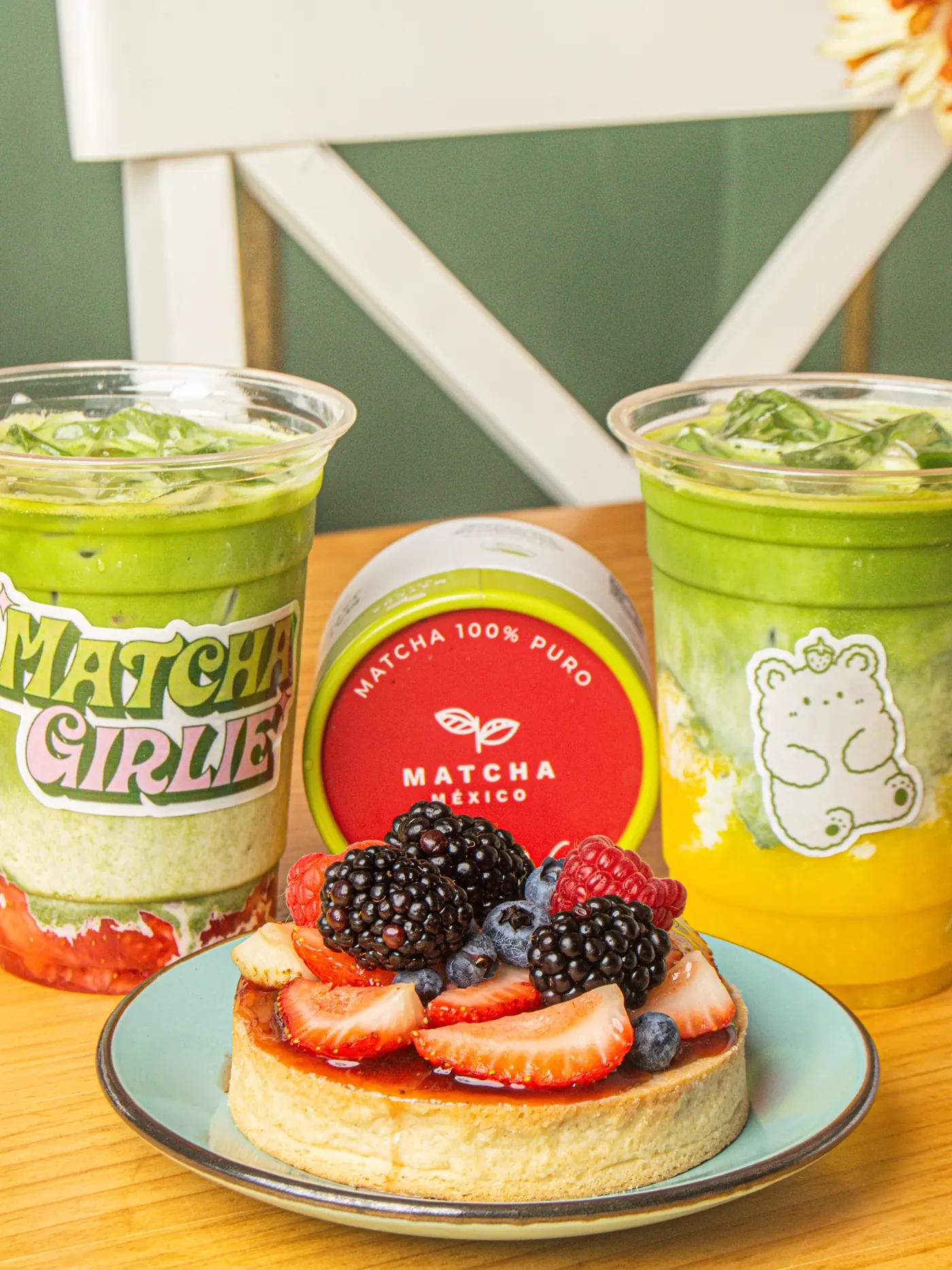 Matcha latte y bowl de frutos rojos sobre la pared verde del local