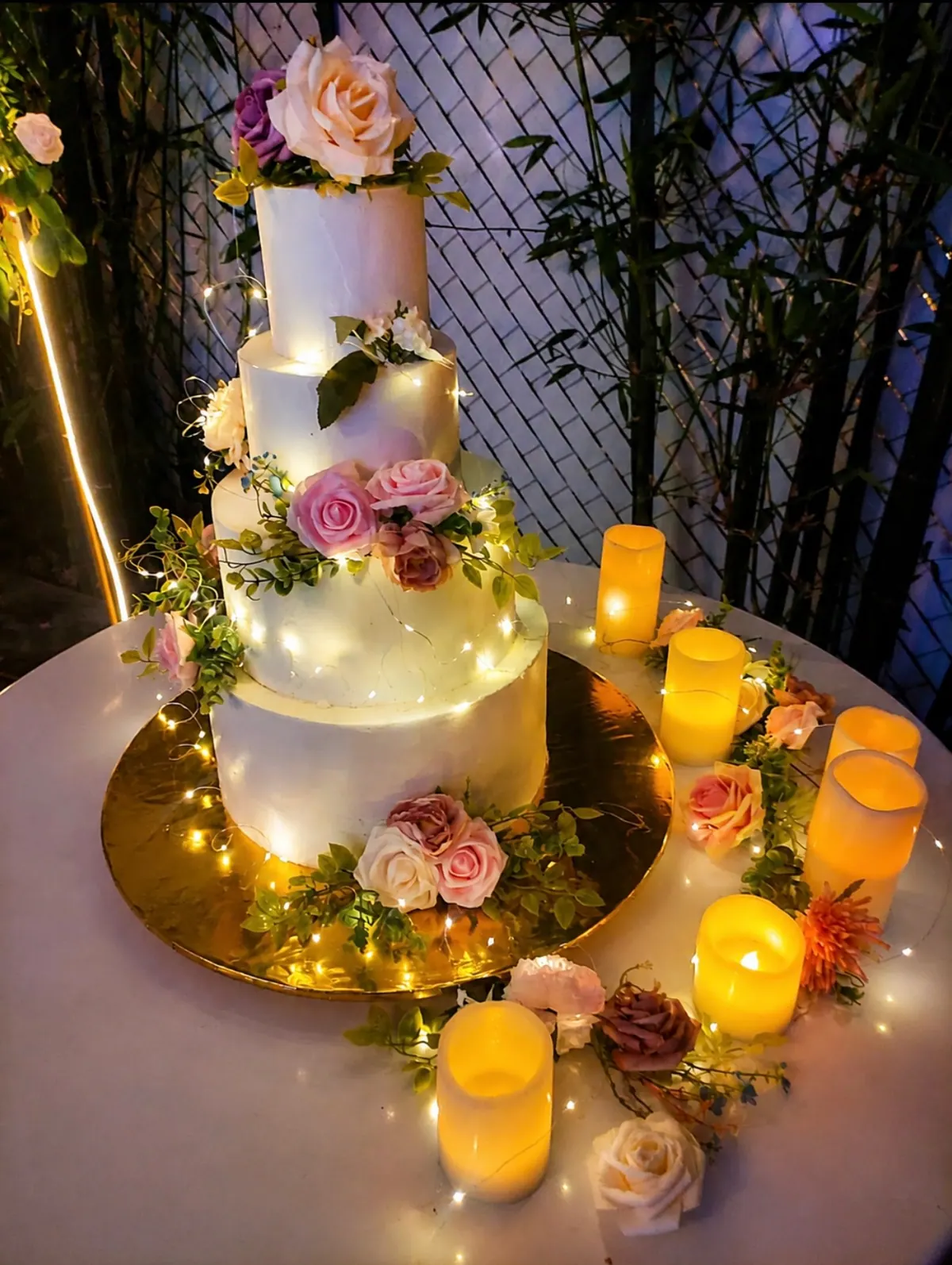 Pastel de boda de tres pisos con flores, entregado con velas encendidas